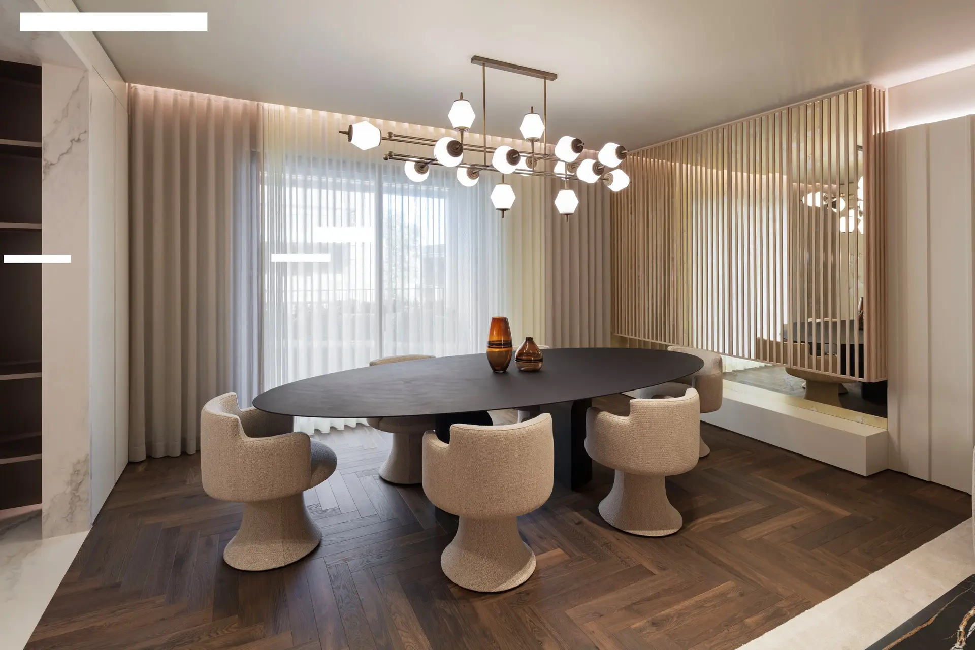 Dining room with a dark oval table, cream chairs and a cluster of glass globe lights