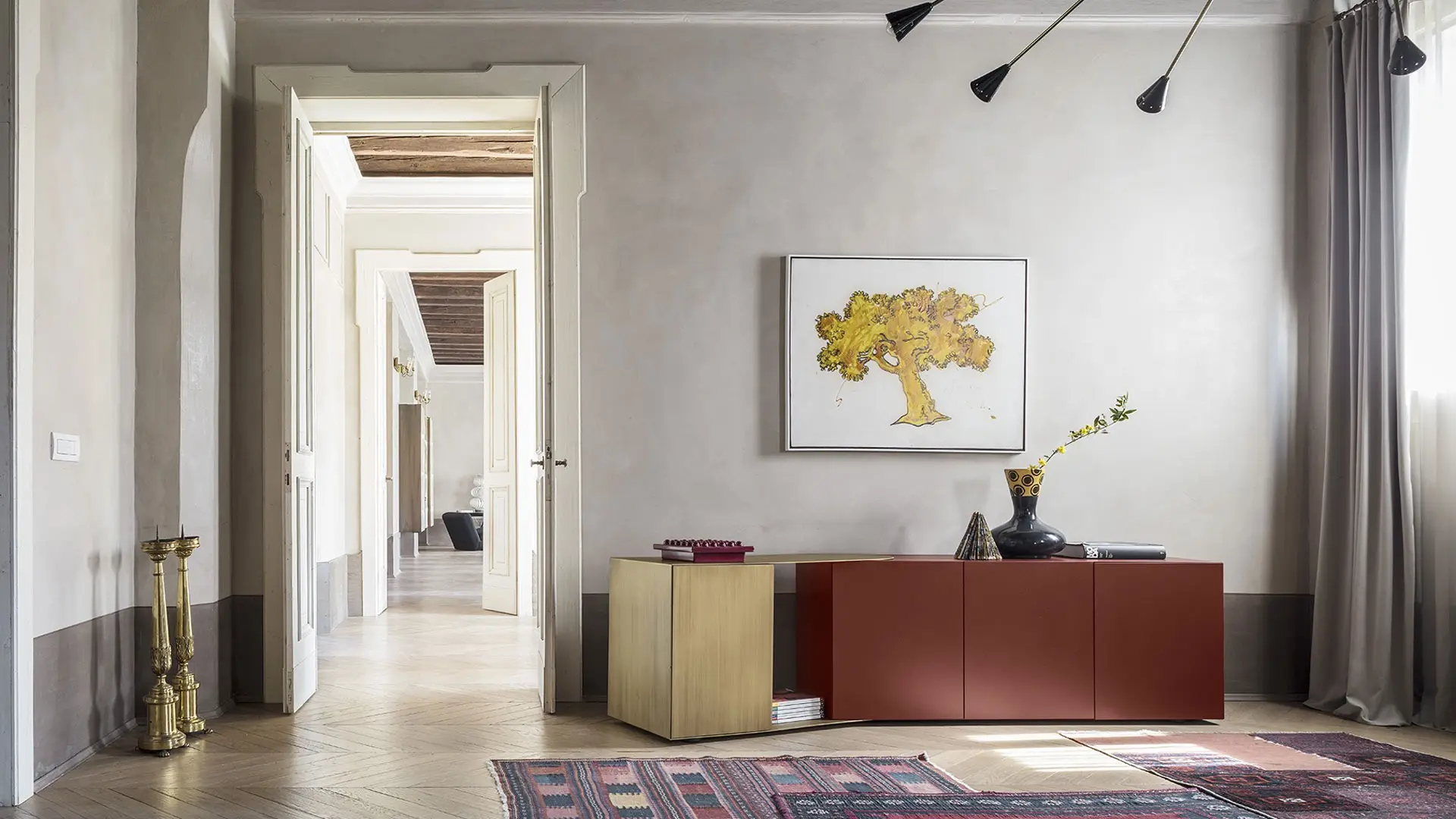 Red and gold sideboard with a yellow artwork in a pale room with old herringbone floors