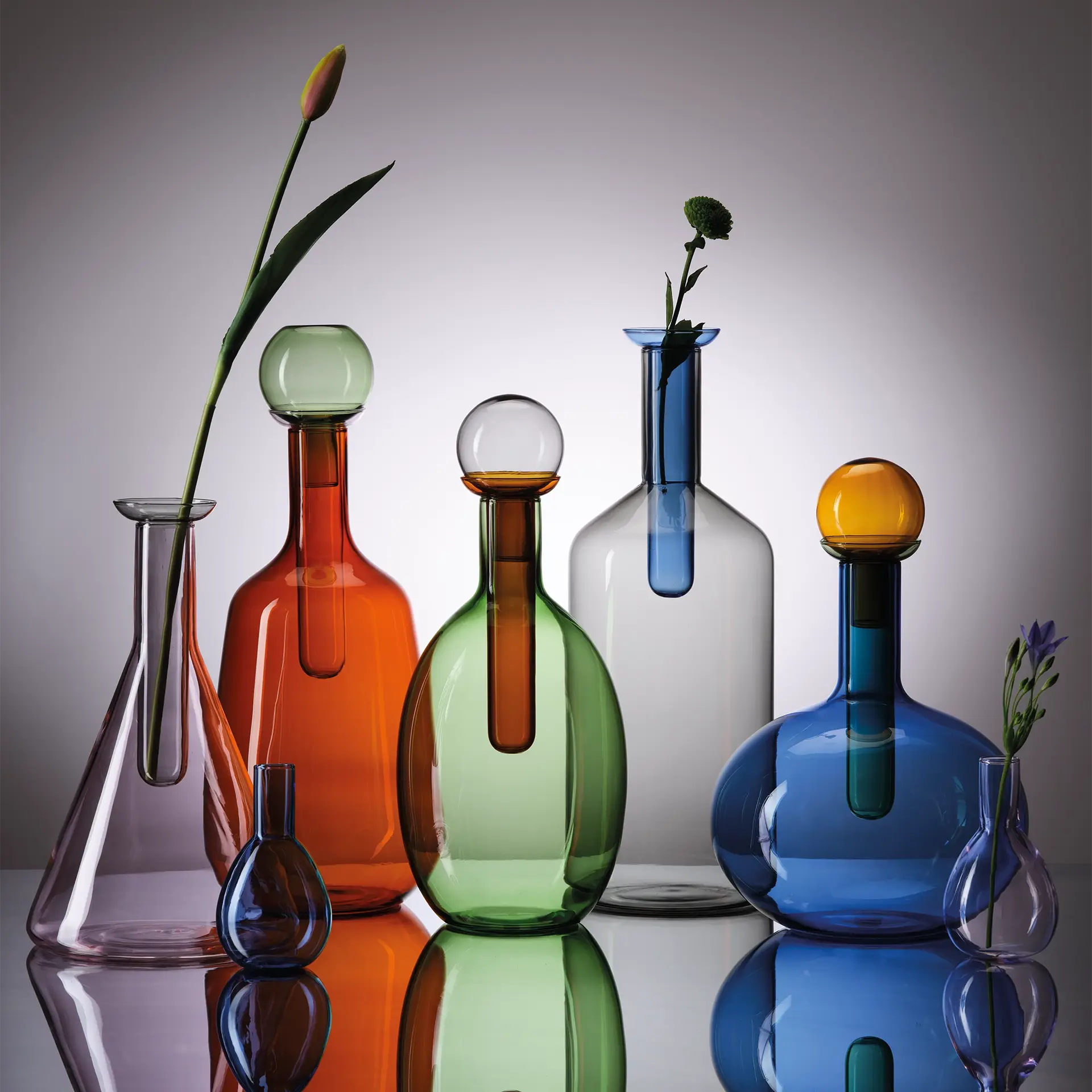 Coloured glass bottles and decanters in orange, green and blue with glass stoppers