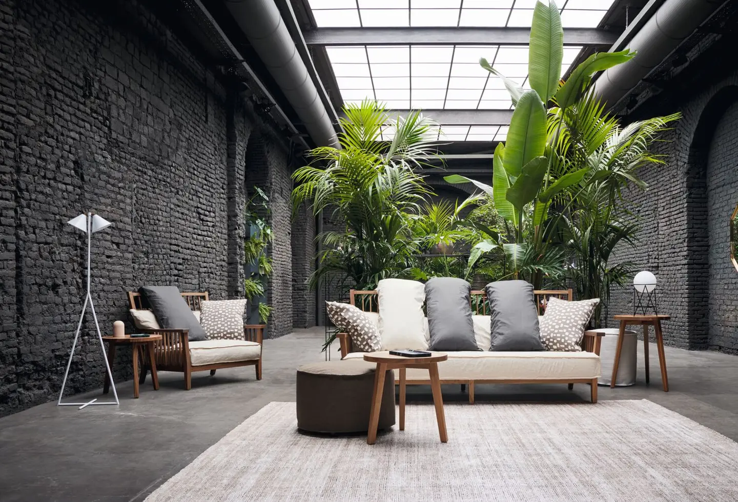 Sofa and armchairs in a brick-walled loft filled with palms