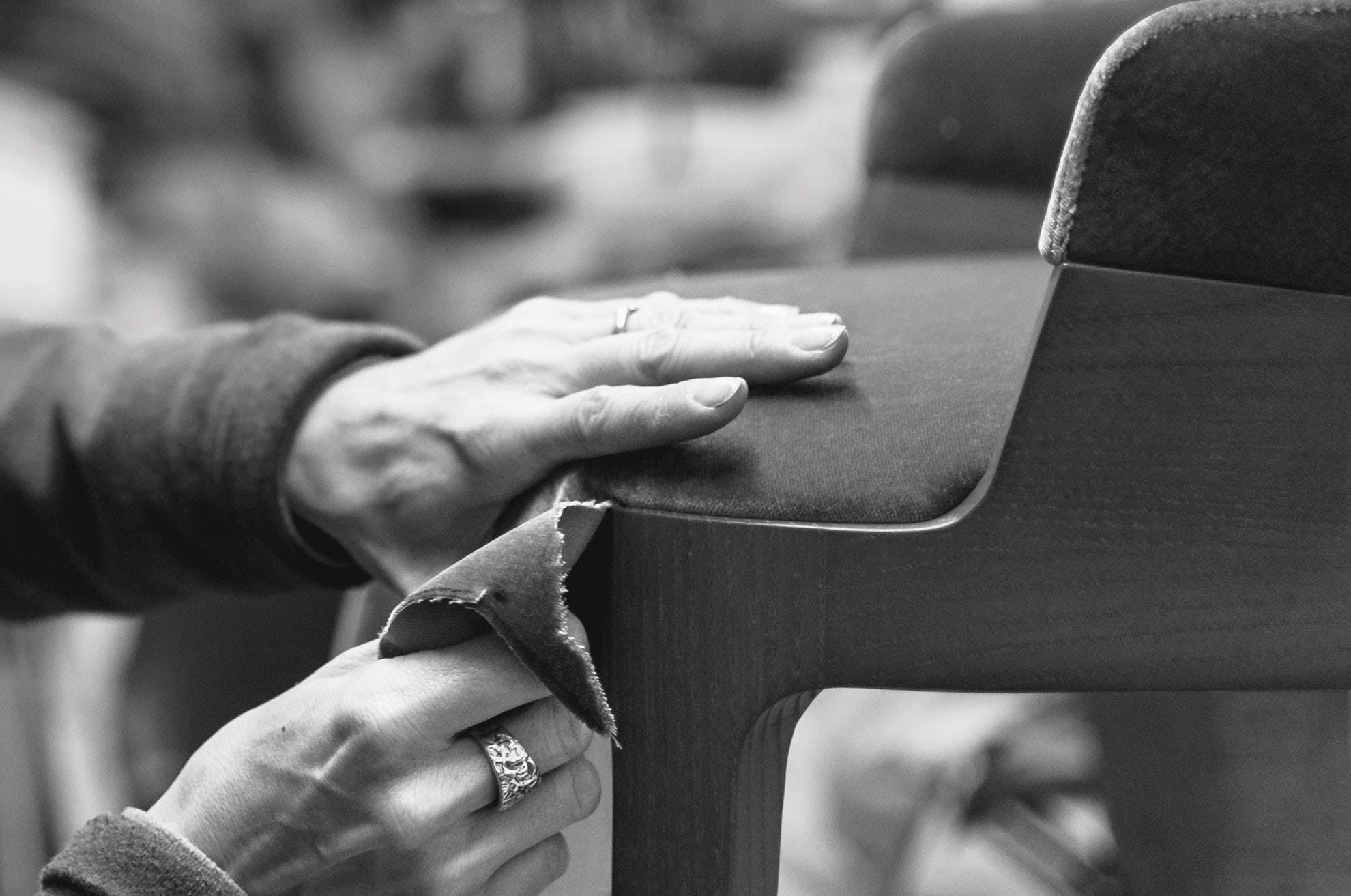 Black-and-white close-up of hands smoothing the upholstery of a chair