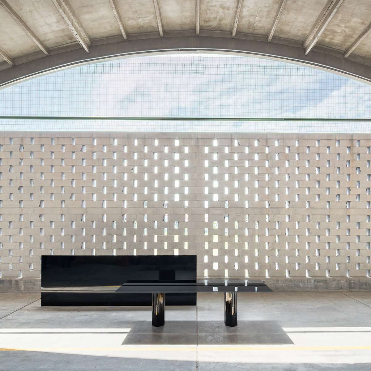 Low black sideboard before a perforated brick screen under a vaulted roof