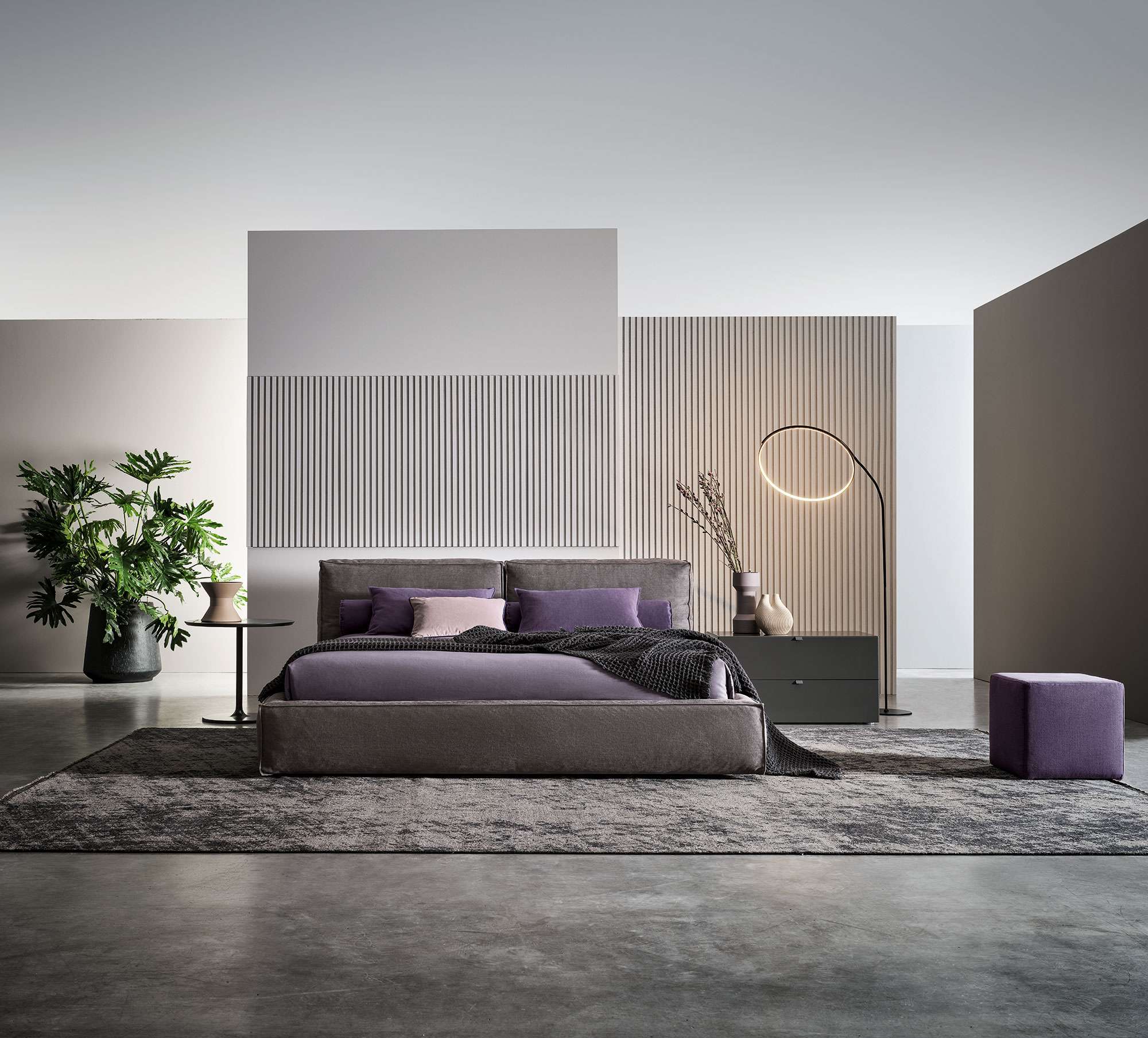 Upholstered bed with purple cushions in a pale room with slatted panels