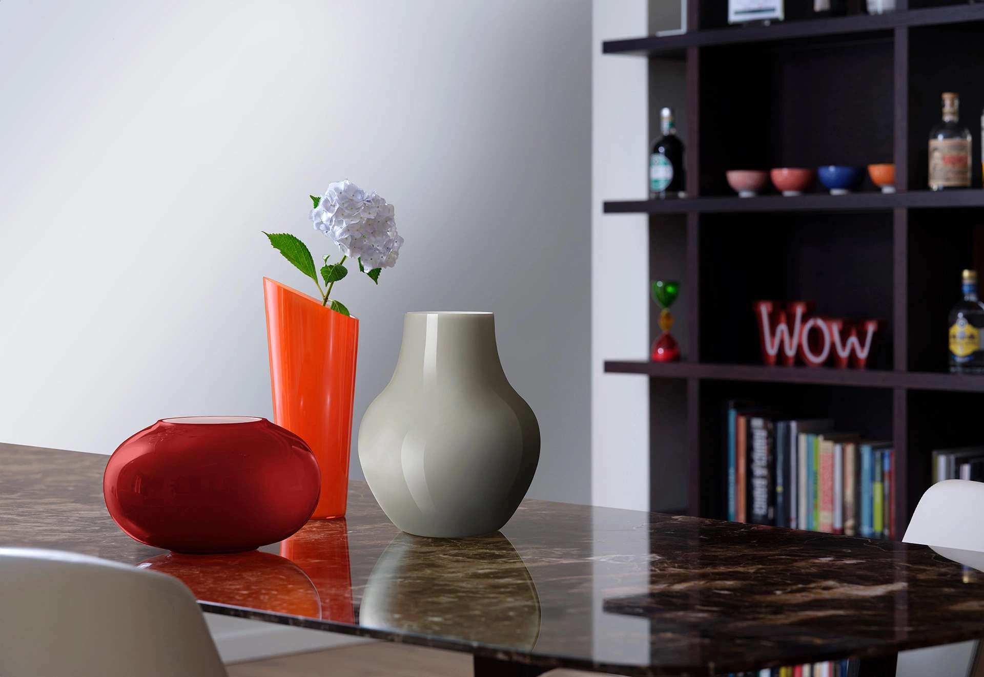 Grey and orange glass vases on a marble table in front of a bookcase