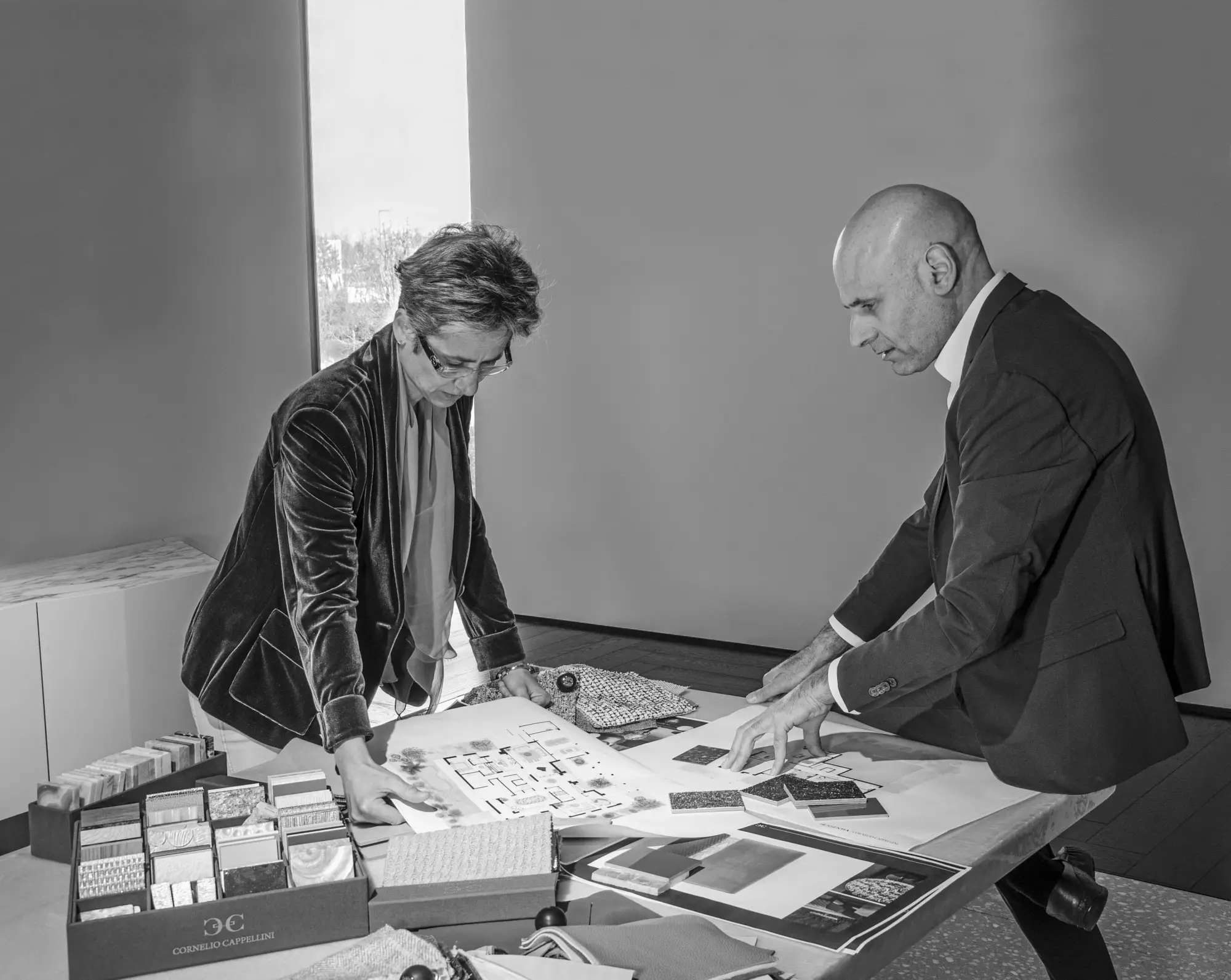 Two people choosing materials at a table covered in samples