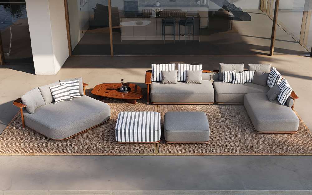 Grey outdoor modular sofa and striped poufs on a stone terrace