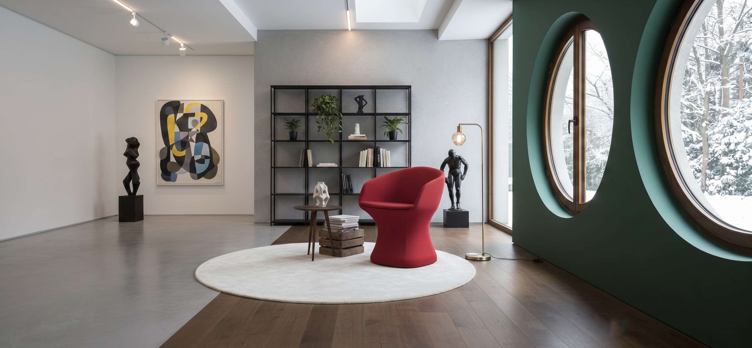 Red armchair on a round rug in a gallery-like living room with sculptures