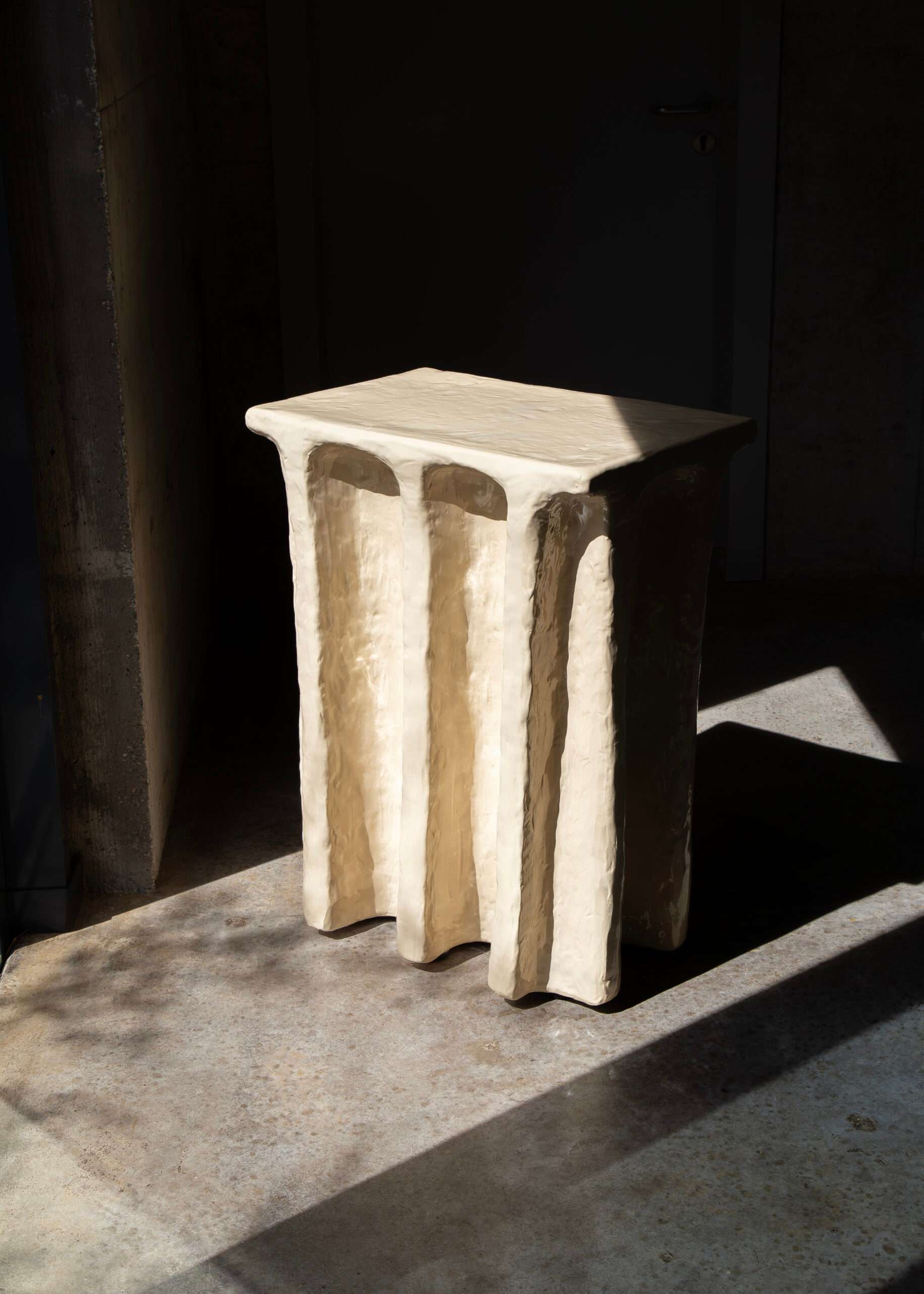 Cream side table with draped legs in raking light