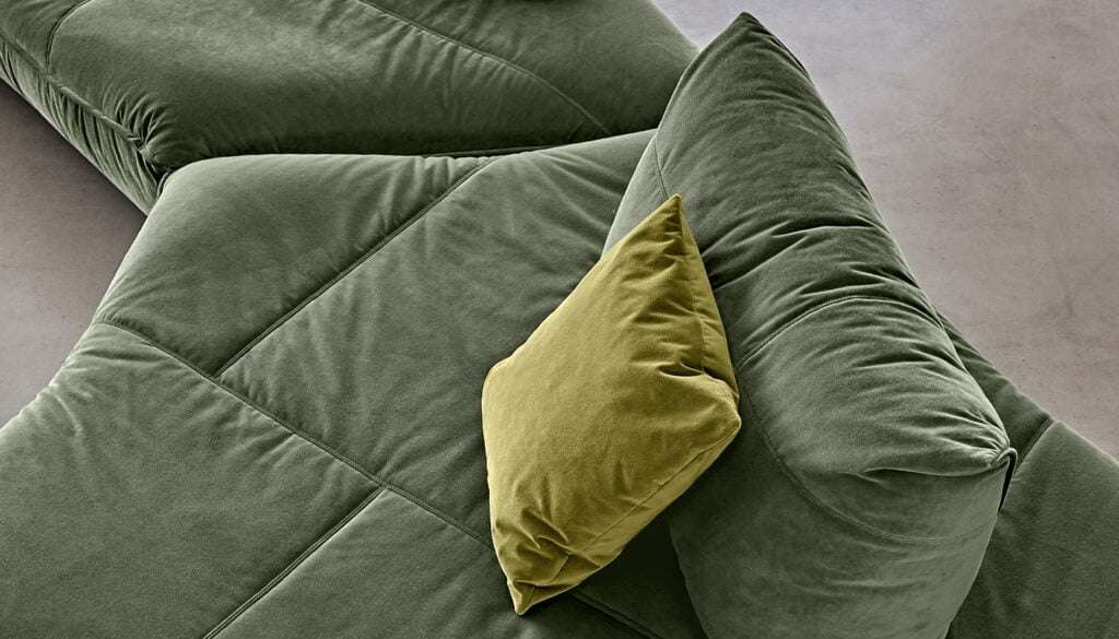 Green velvet sofa with an olive cushion, close up