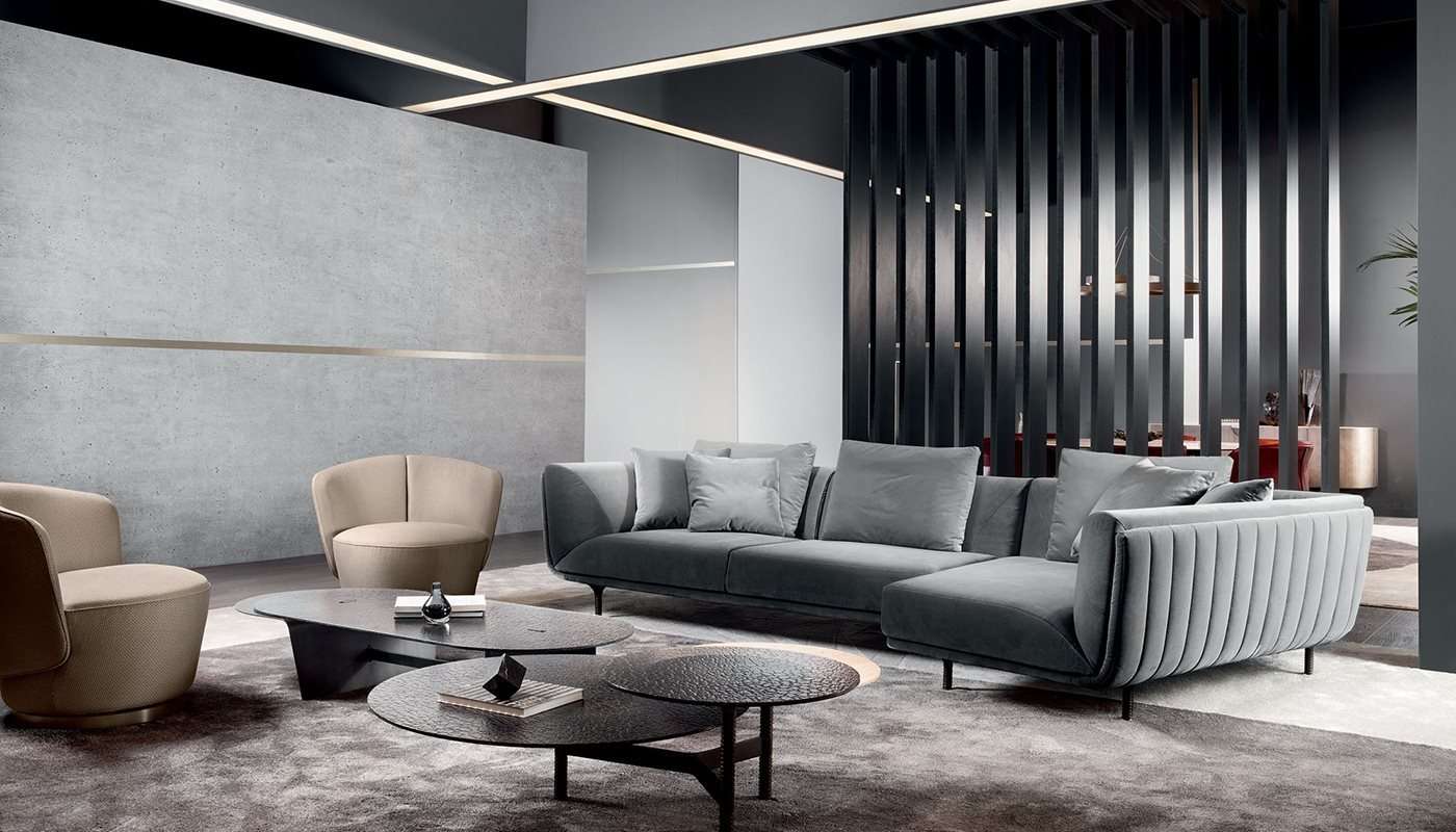Grey sofa with a curved back and round dark coffee tables against black slats