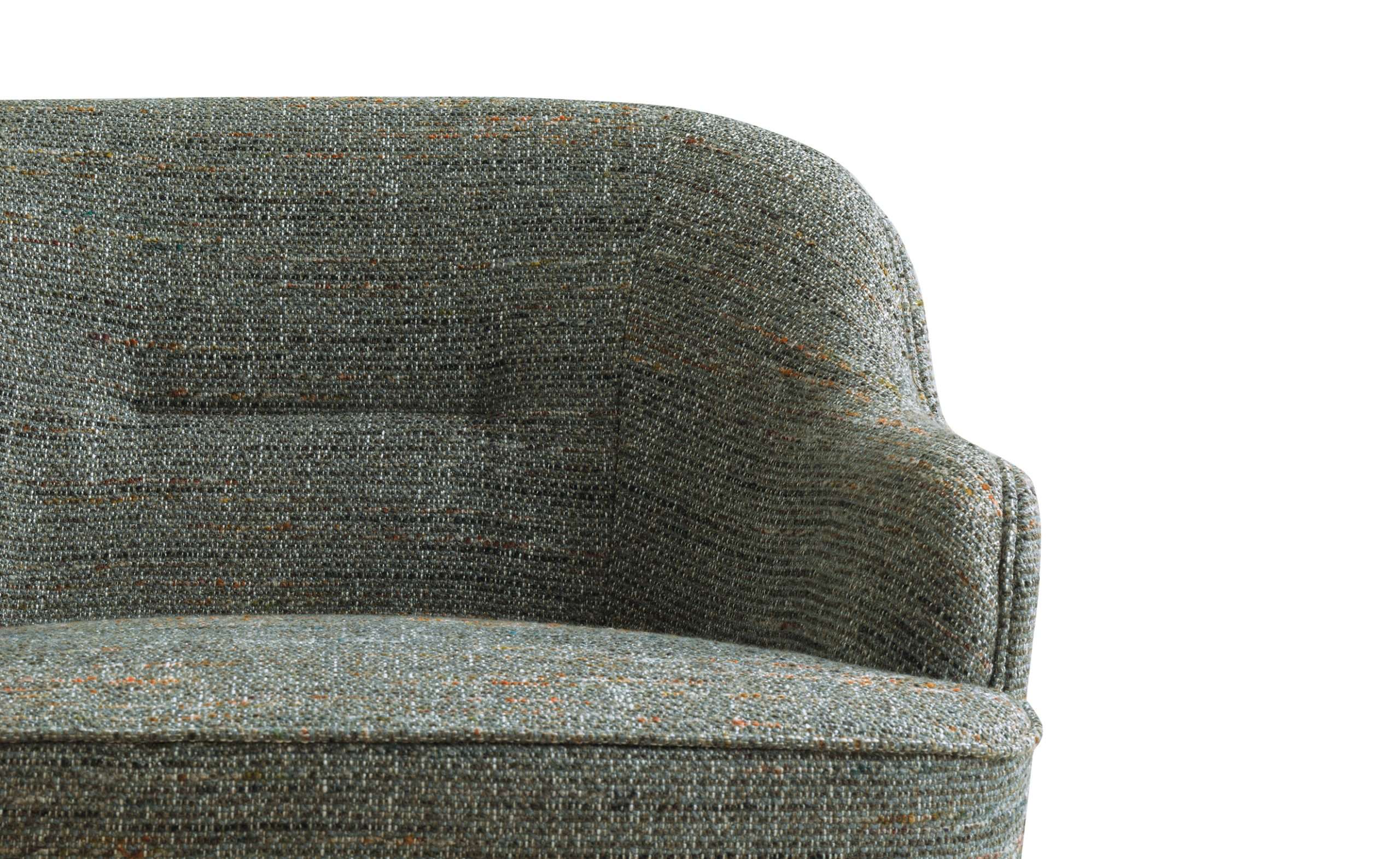 Close-up of an armchair upholstered in a green-grey textured fabric