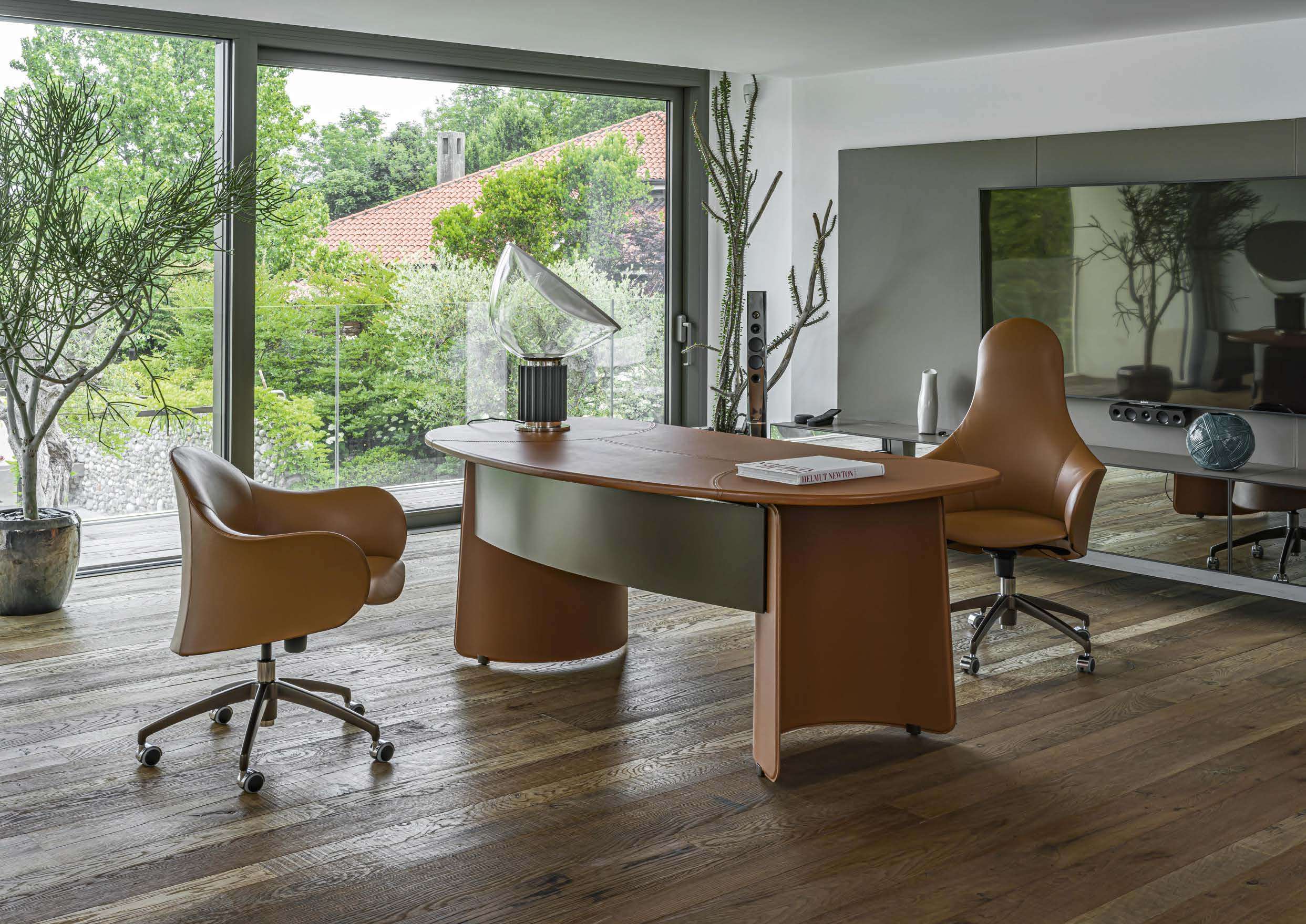 Tan leather desk and swivel armchairs in a study facing a garden