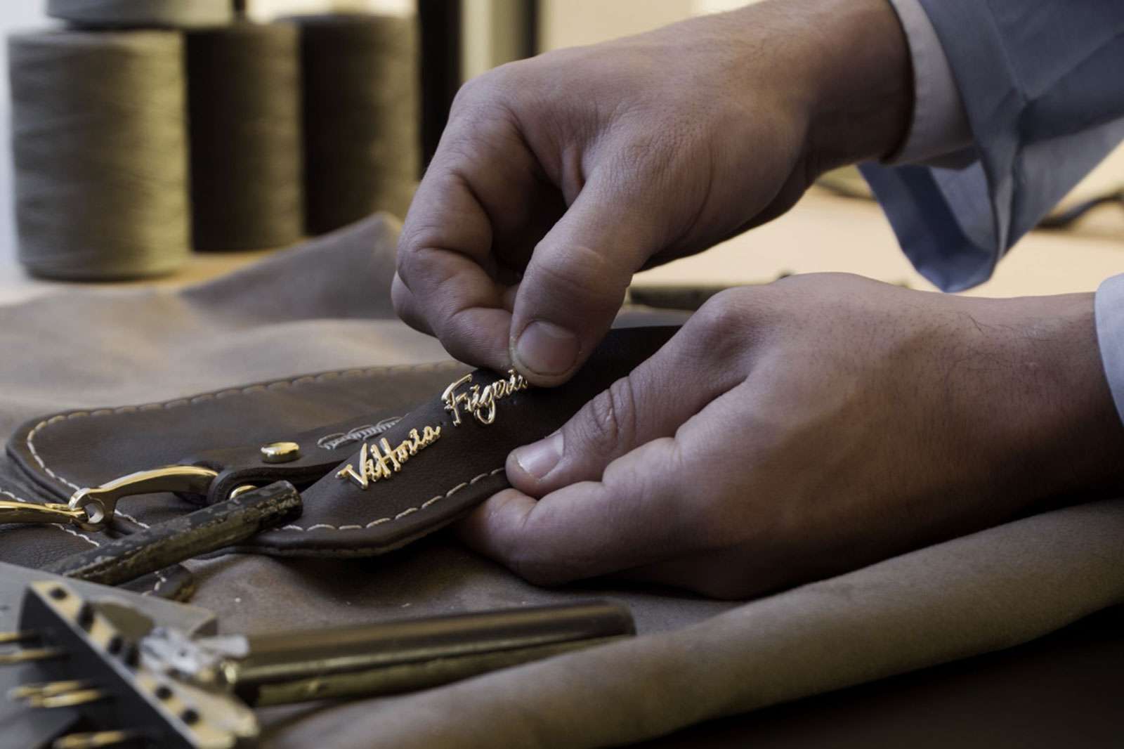 Hands stitching a leather label by hand