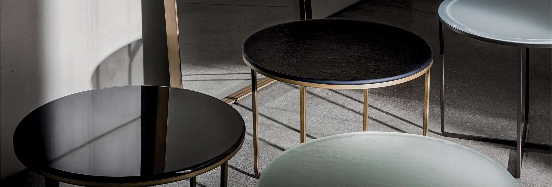 Round black glass side tables with slim brass frames