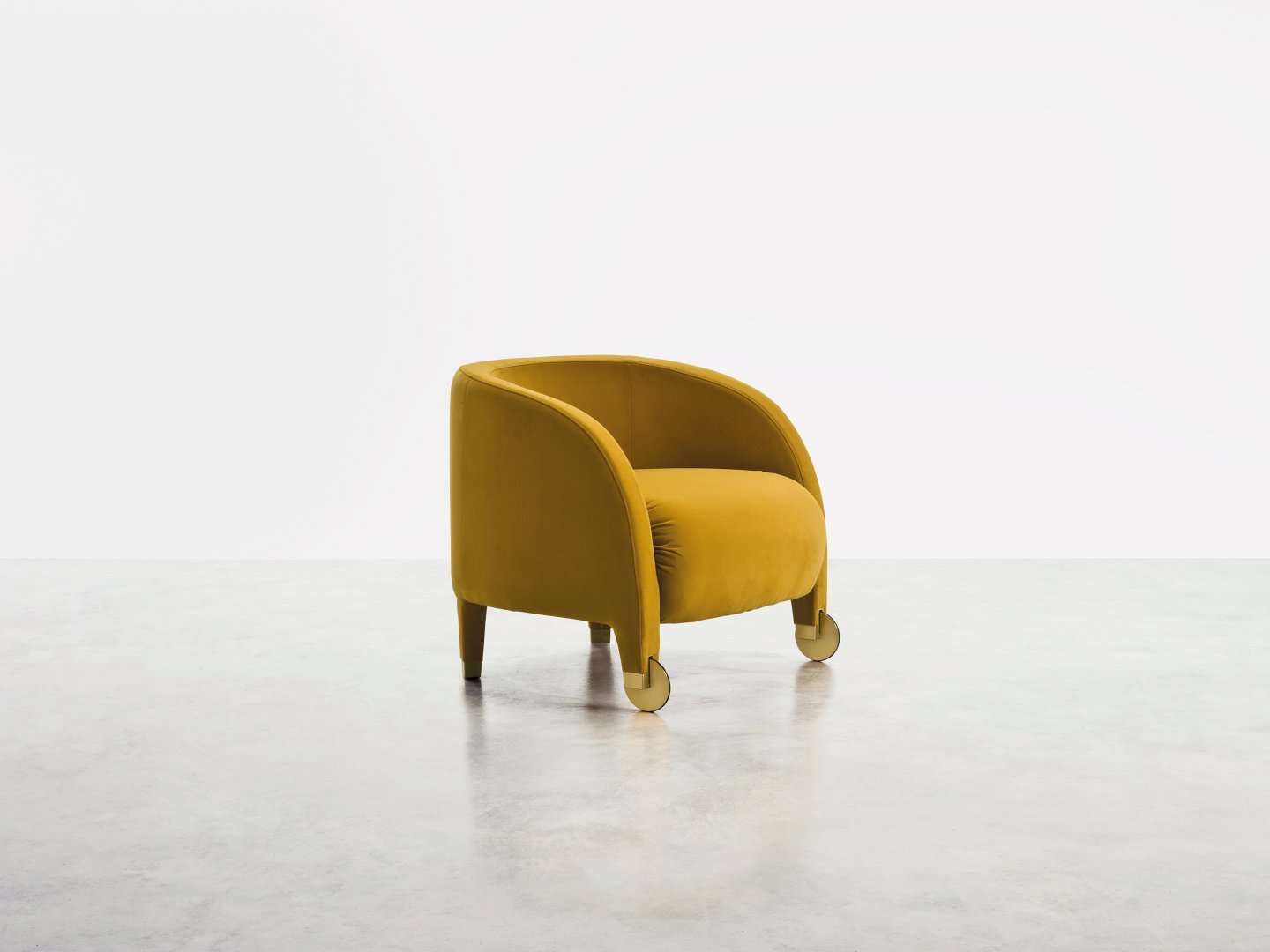 Mustard armchair with a rounded back on brass castors