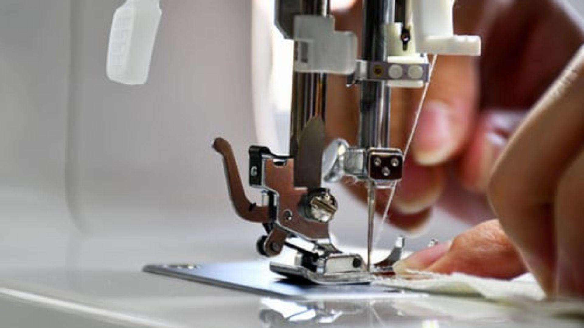 Hands guiding upholstery fabric through a sewing machine