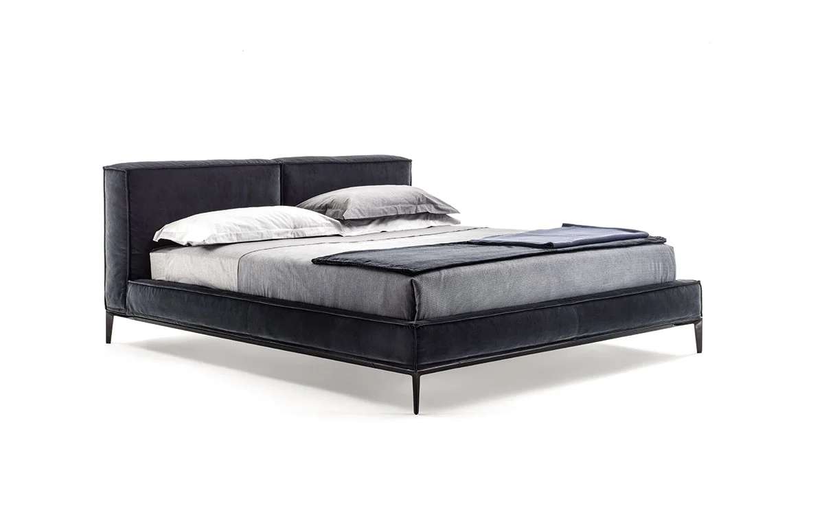 Bed with a dark leather headboard and grey bedding