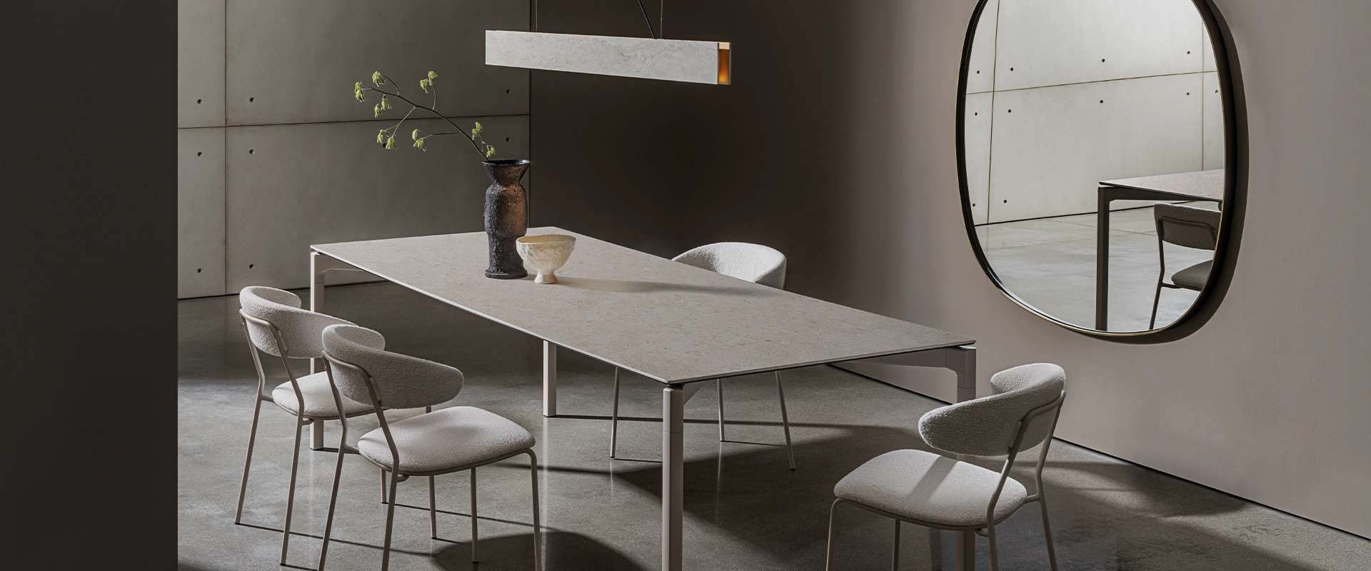 Long pale dining table with white chairs and a linear pendant