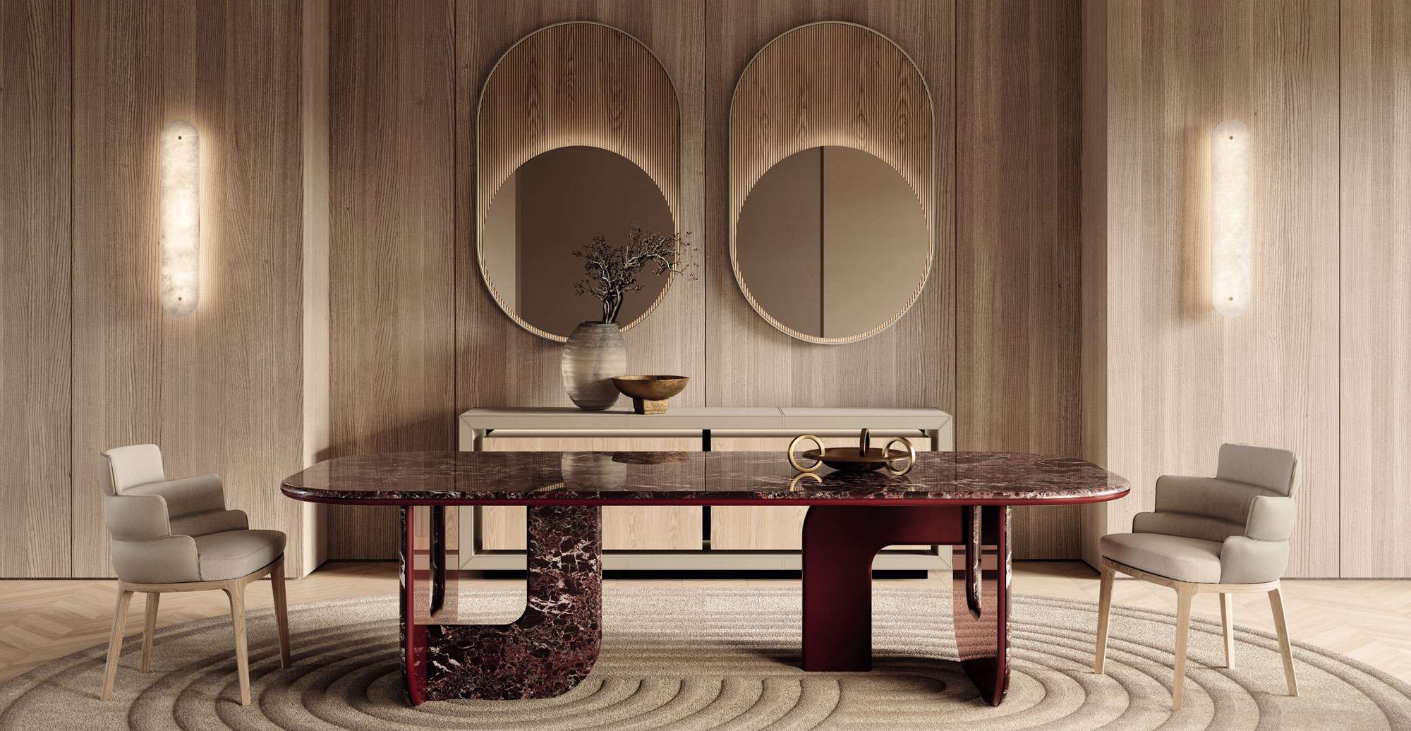 Dark red marble dining table and upholstered chairs before two oval mirrors on a timber wall