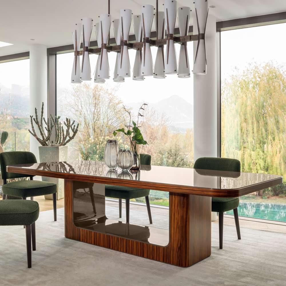 Walnut dining table with a glossy top and green velvet chairs before a garden and a pool