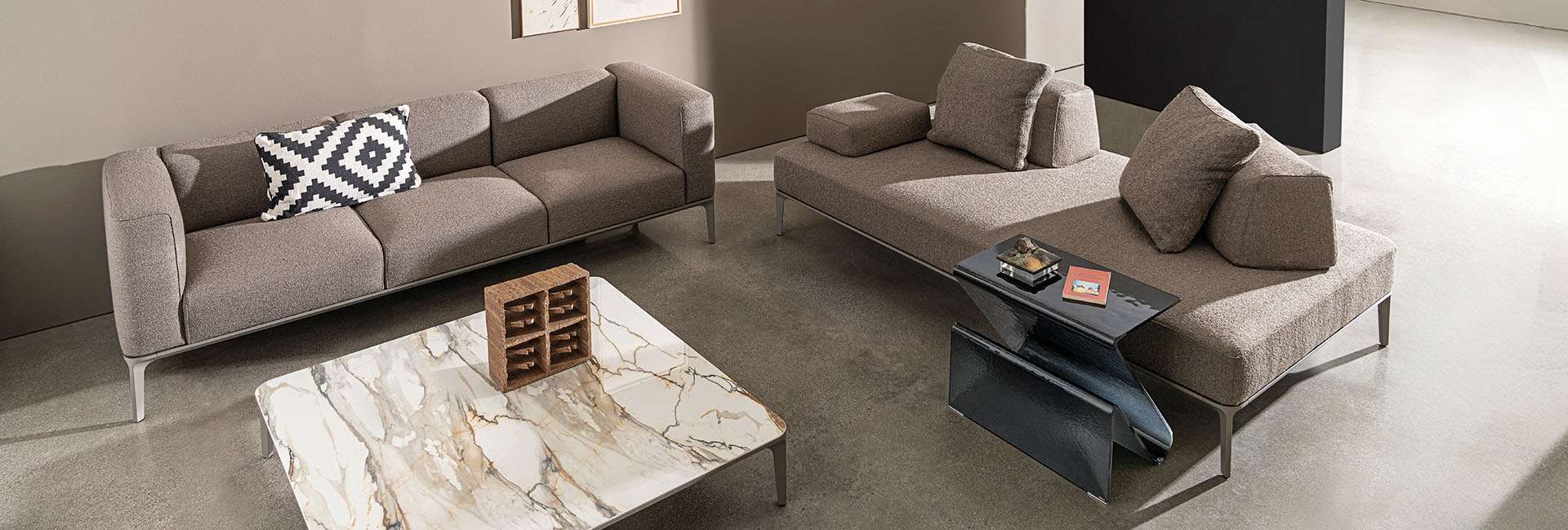 Grey sofas around a marble coffee table and a dark glass side table