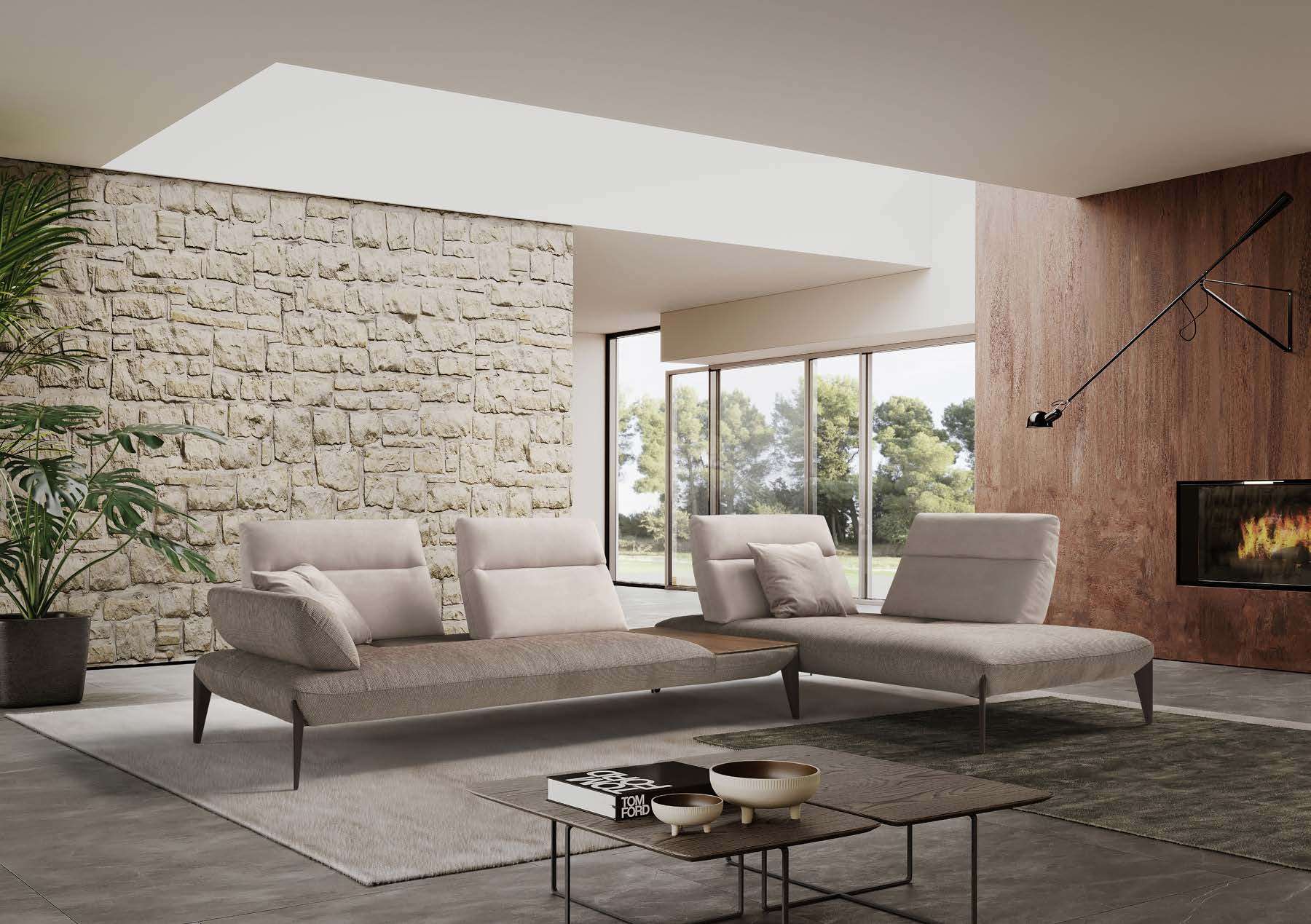 Pale corner sofa in front of a rough stone wall and a fireplace