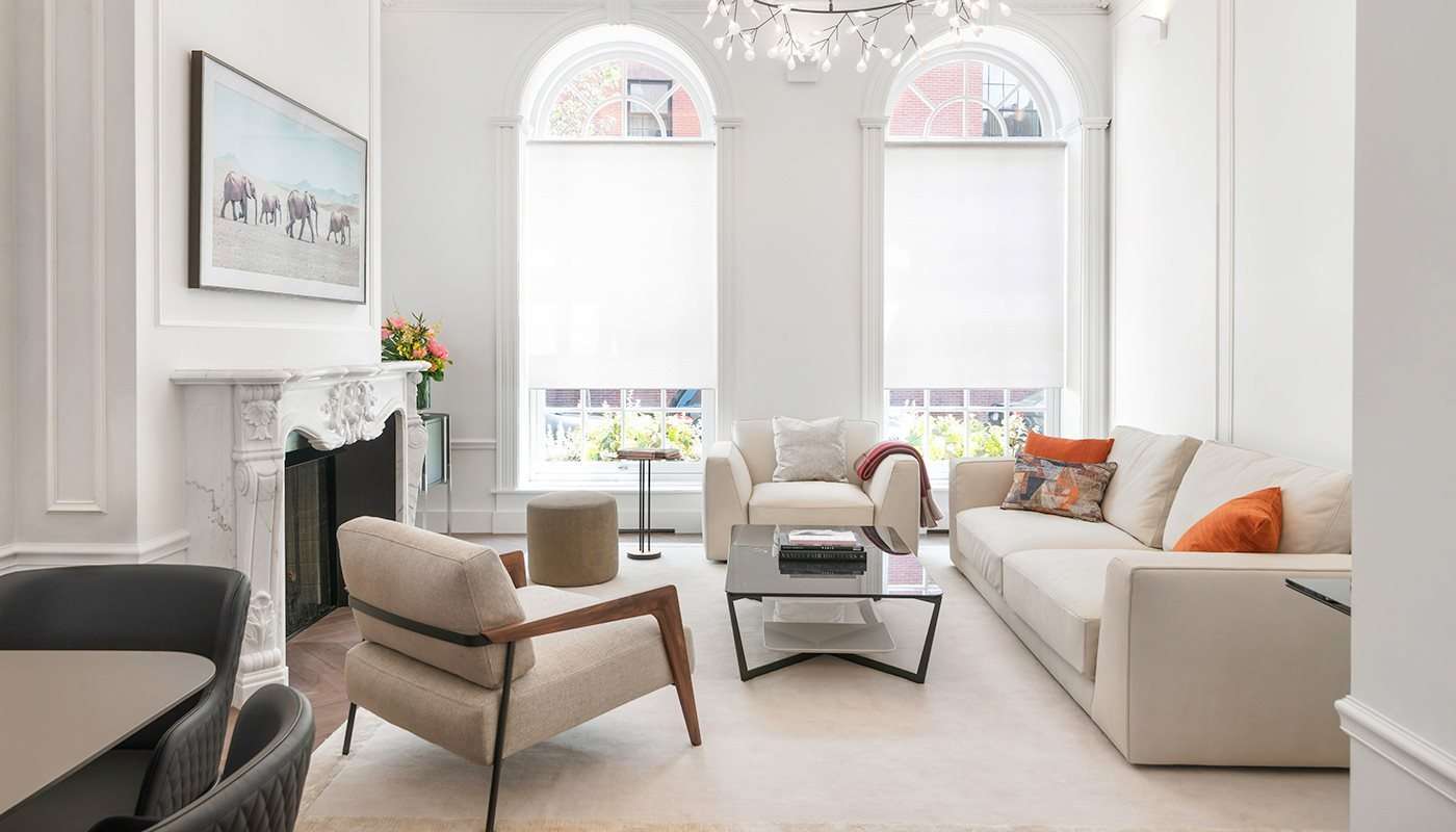 Living room with cream sofas and armchairs below tall arched windows