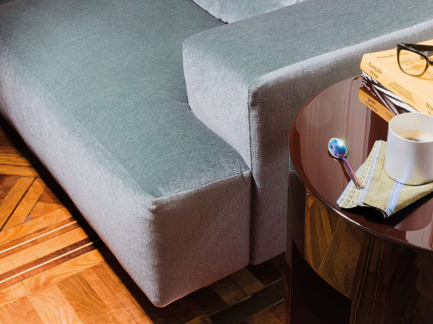 Corner of a pale blue sofa beside a lacquered side table
