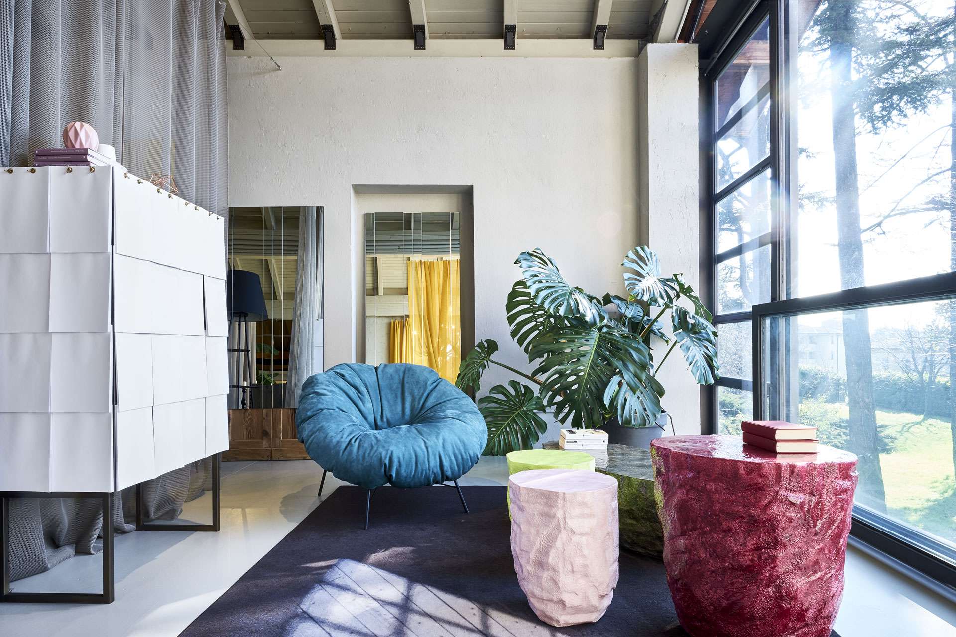 Blue shell armchair and pink stone side tables beside a white cabinet