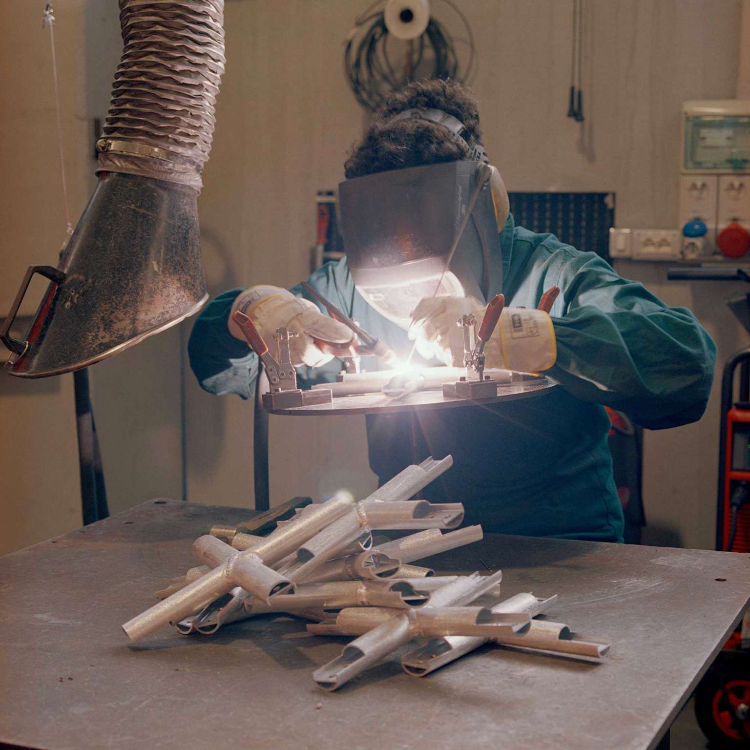 A welder joining aluminium parts behind a protective visor