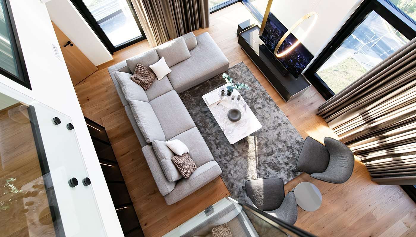Corner sofa, marble coffee table and dark armchairs seen from above