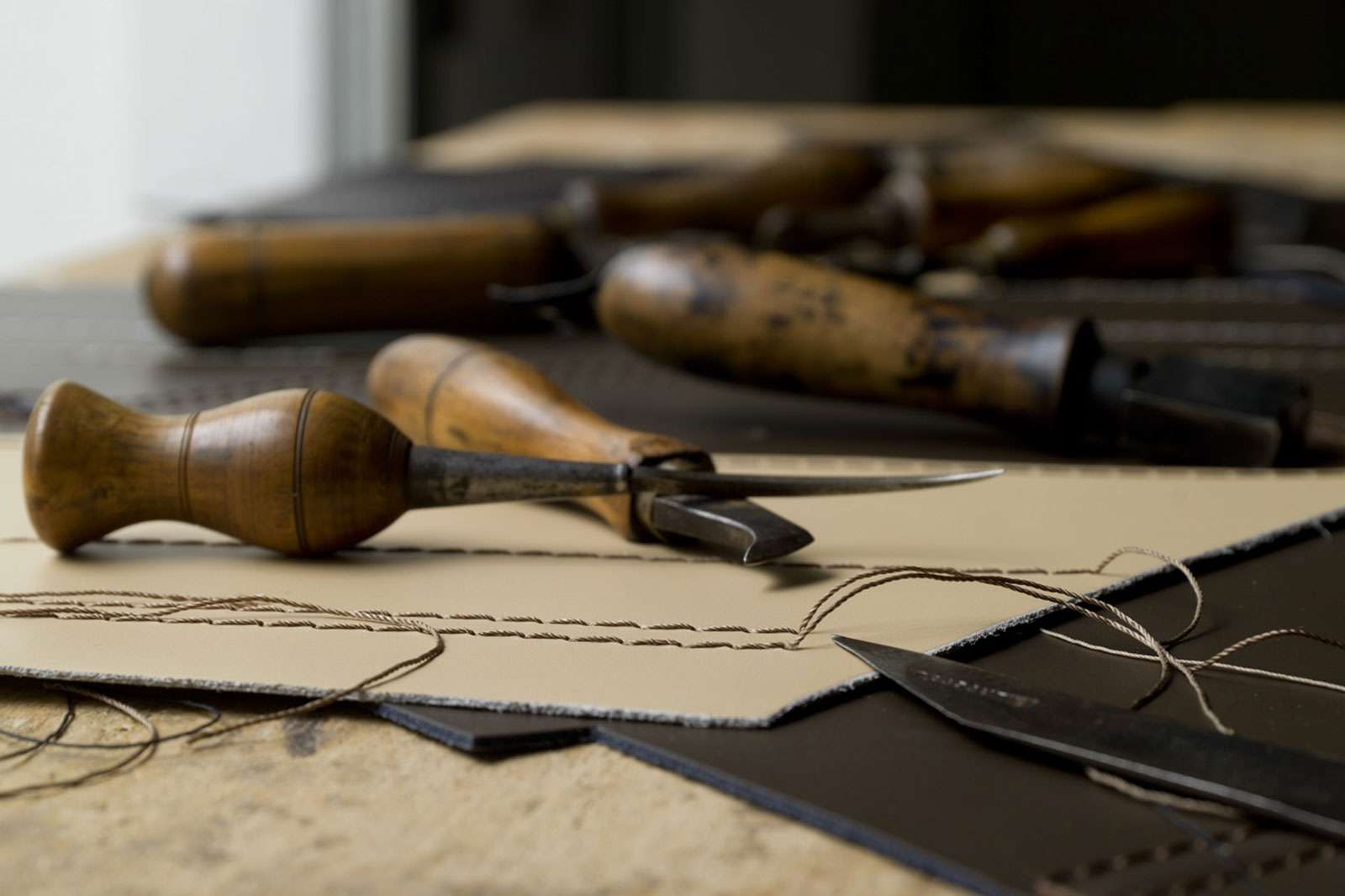 Leatherworking tools laid on hides and stitched samples