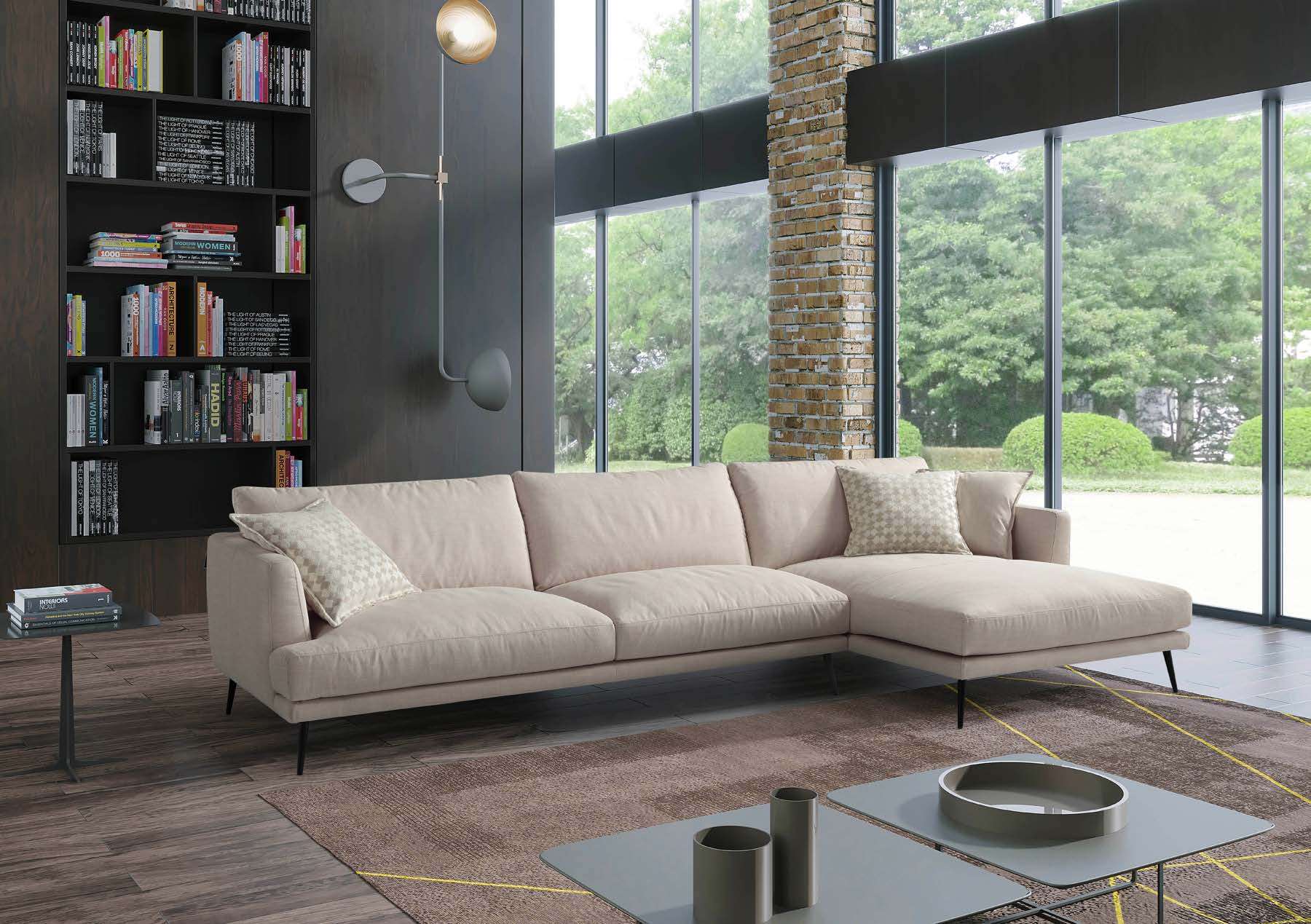 Cream corner sofa beside a bookcase and full-height windows onto trees