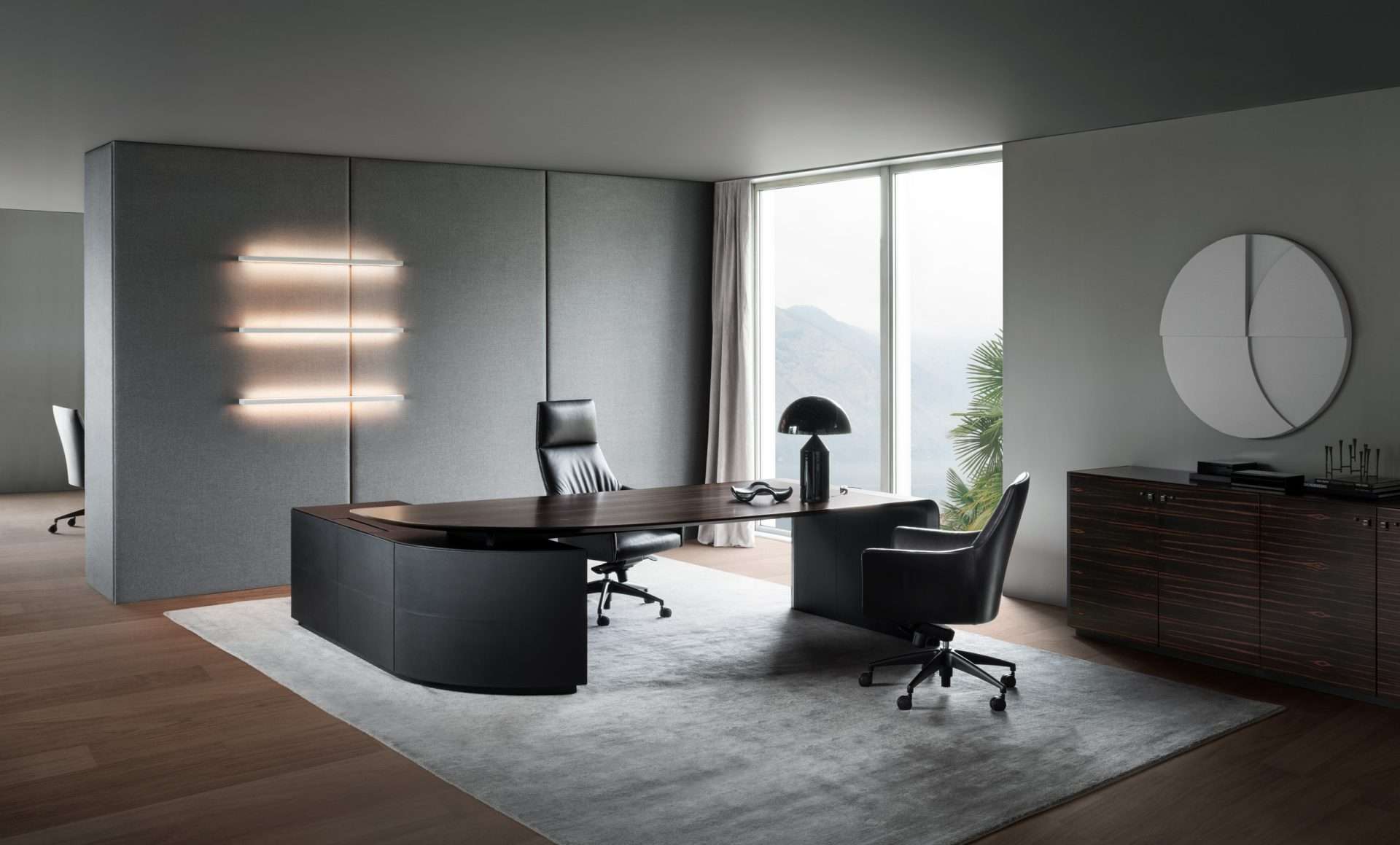 Dark executive desk and leather chairs in an office with a mountain view