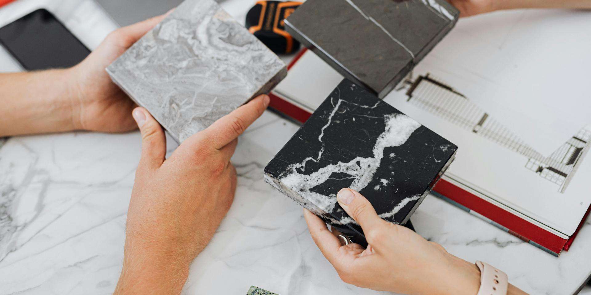 Hands comparing black and grey marble samples
