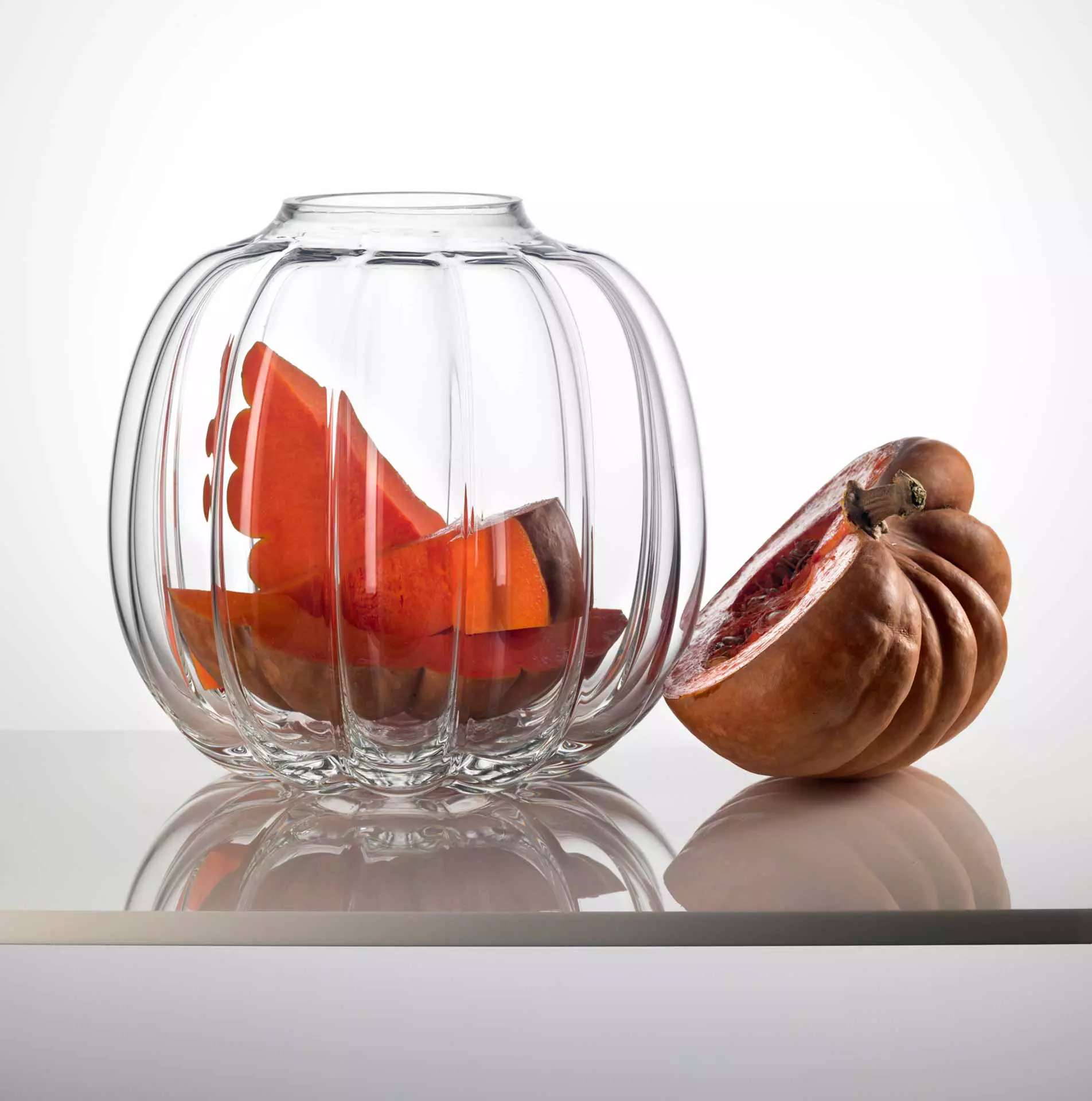 Ribbed clear glass jar beside a cut pumpkin