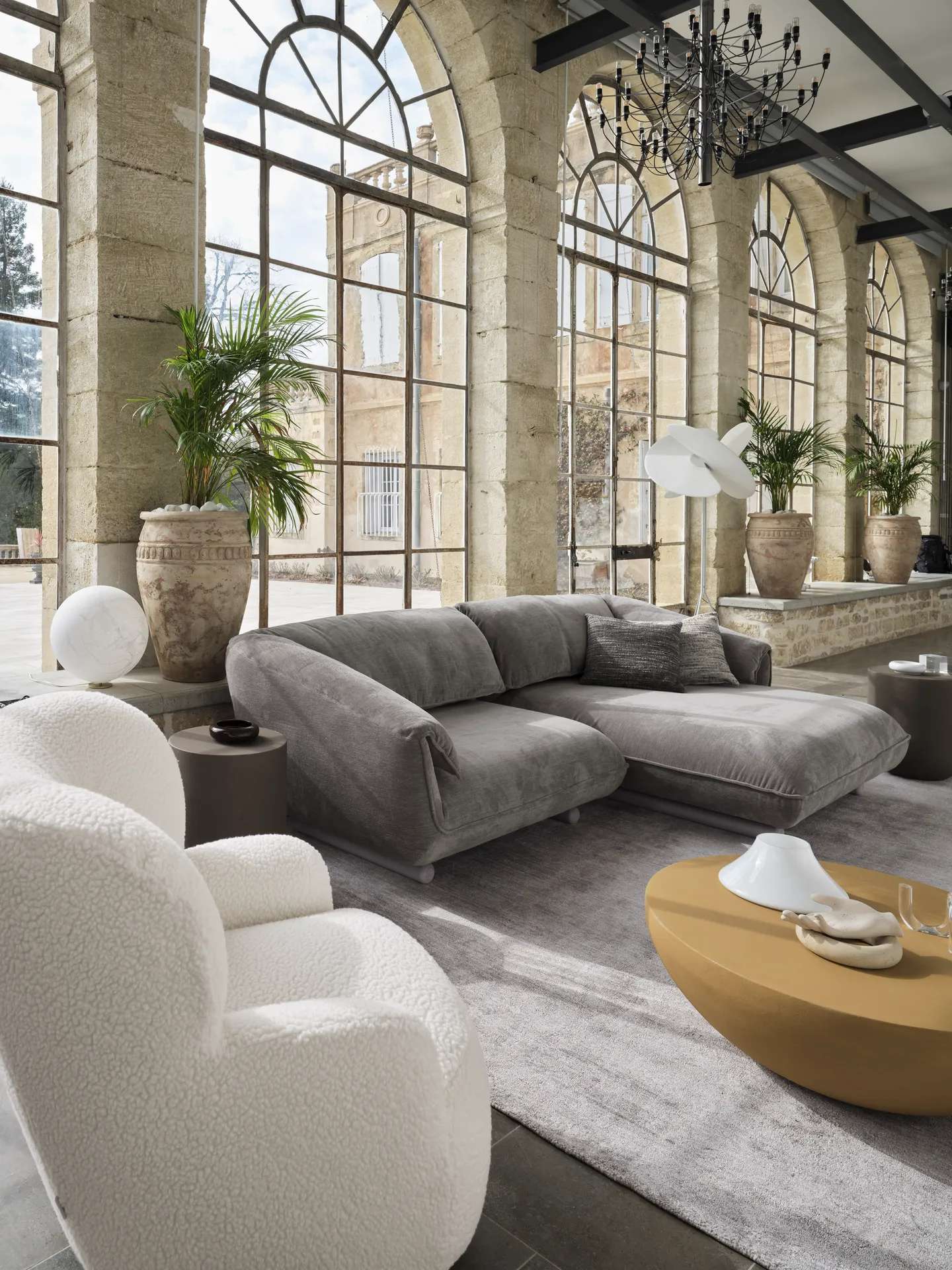 Grey chaise sofa in a stone conservatory with palms