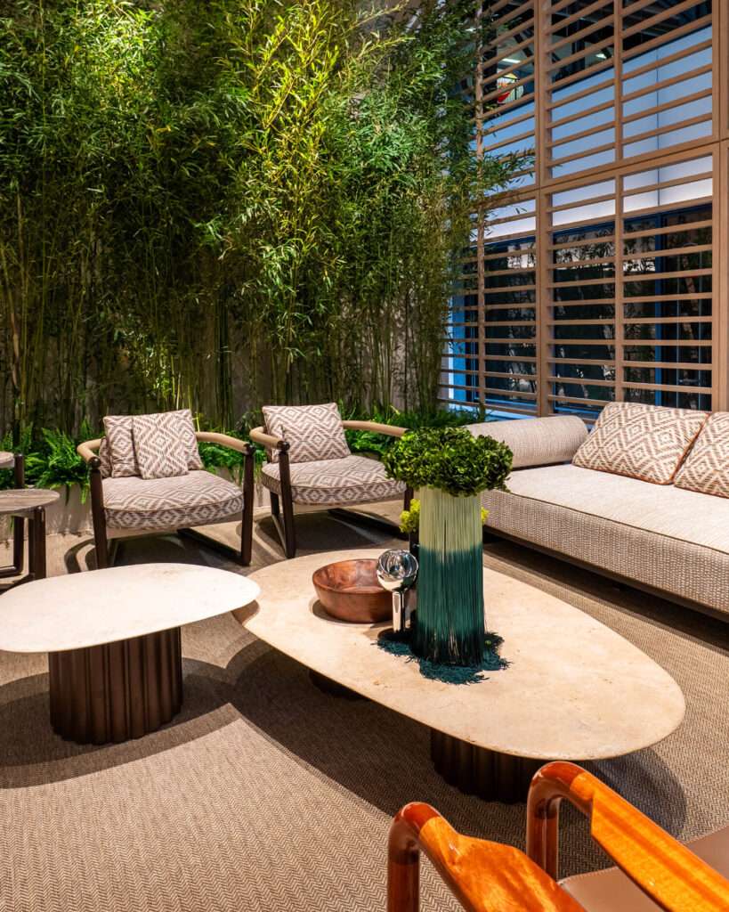Woven outdoor armchairs around a round table, with a planter between them